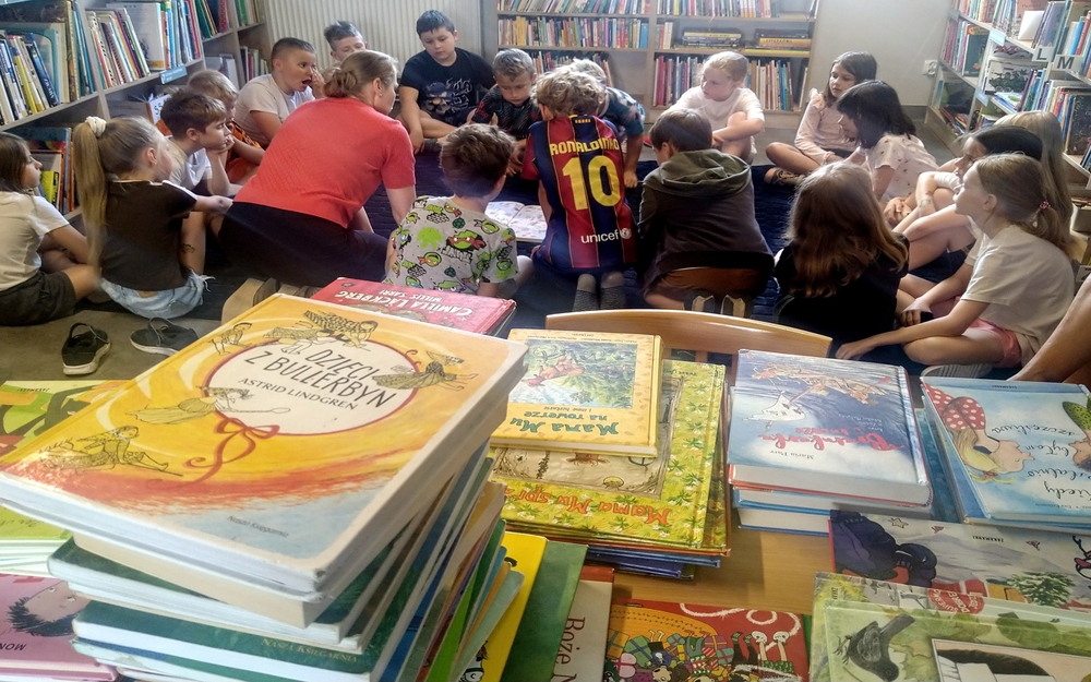 uczniowie szkoły w kiełczowie w bibliotece na spotkaniu palcem po mapie