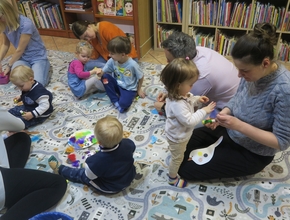 dzieci z opiekunami kolorują ptaki wycięte z papieru