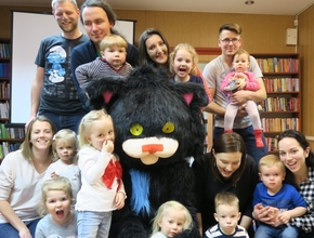Wielki czarny, pluszowy kot w towarzystwie dzieci i dorosłych w czytelni w Długołęce 