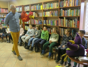 pan poeta prezentuje książki na spotkaniu z uczniami SP w bibliotece w długołęce