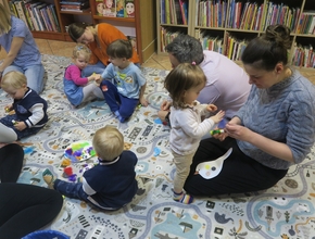 dzieci z opiekunami kolorują ptaki wycięte z papieru